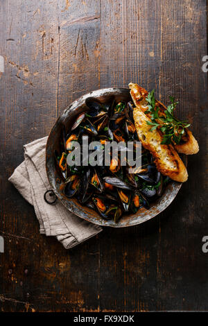 Mussels with parsley and bread toasts on dark background Stock Photo