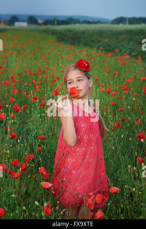 girl in red dress walks at poppy field Stock Photo