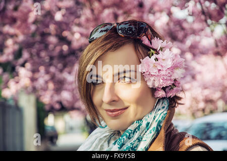 Young caucasian woman posing with sakura flowers in sunset. Beauty and nature. Stock Photo