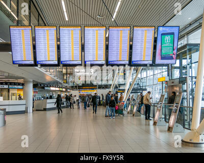 Flight departures boards and passengers in departure terminal of Schiphol Amsterdam Airport, Netherlands Stock Photo
