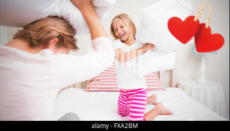 Composite image of mother and daughter fighting with pillows Stock Photo