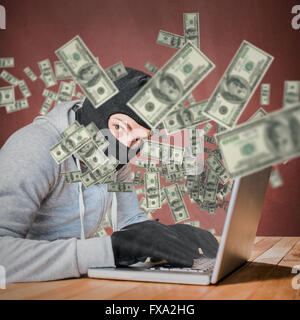 Composite image of focused thief with hood typing on laptop Stock Photo