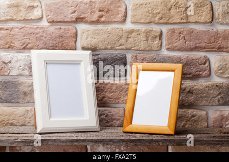 Blank photo frames on shelf in front of brick wall Stock Photo