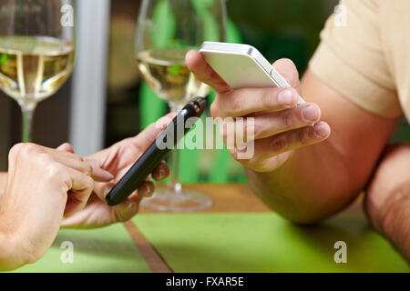 Couple using their smartphones at the same time in a restaurant Stock Photo