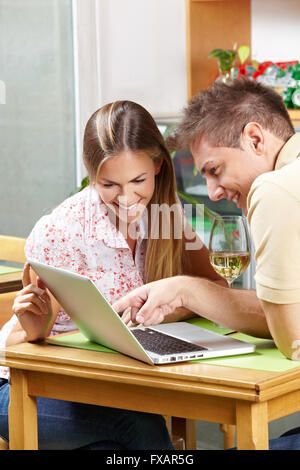 Happy couple in café looking together at laptop computer Stock Photo