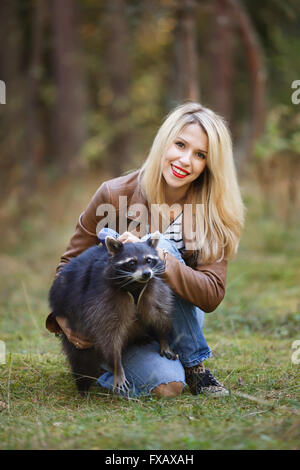 Portrait of attractive young woman with raccoon in a forest Stock Photo