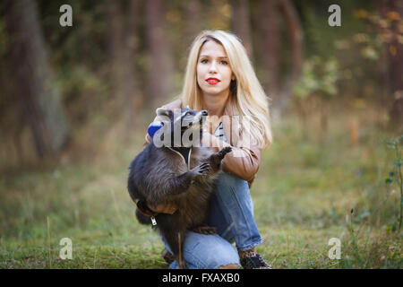 Portrait of attractive young woman with raccoon in a forest Stock Photo
