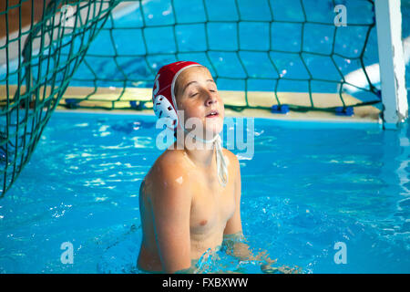 gatekeeper kid floating in the water during a water polo match Stock Photo