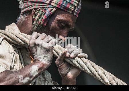 A worker is dragging a heavy pull rope in a shipbreaking yard in Chittagong. Once the beach at the shipwrecking places in Chittagong, Bangladesh were white and clean. Today Chittagong is partially soaked with oil and toxic mud. Stock Photo