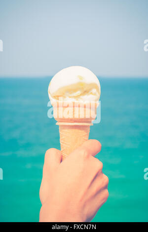 ice cream cone held up to the summer sky background the turquoise sea Stock Photo