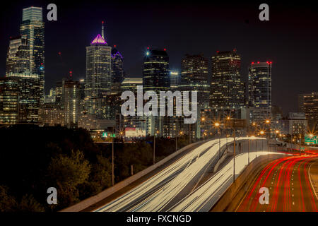 The skyline of Philadelphia is seen in this long exposure, with the light trails of cars on the freeway in the foreground. Stock Photo
