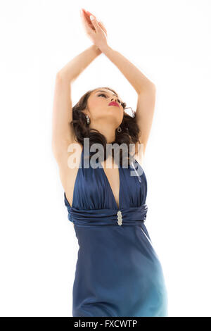 Beautiful young woman in vintage blue dress, half length with arms raised over head. Stock Photo