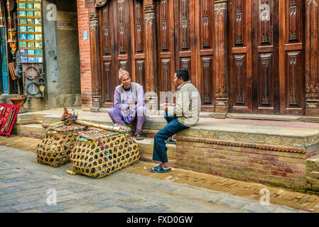 Two aged men carrying hens for sale discuss in the street of Kathmandu Stock Photo