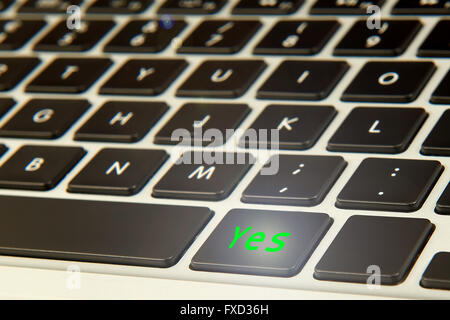 Computer keyboard with a green glowing yes button Stock Photo