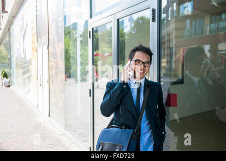Young asian business man talking on mobile phone outside on city street with copy space Stock Photo