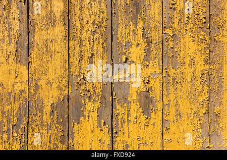 Yellow paint is peeling from a board wall Stock Photo