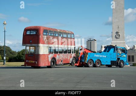 Old derelict red bus being towed. Stock Photo