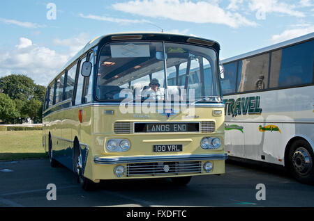 Man in a hat sits in a cream coach with the sign Lands End Stock Photo