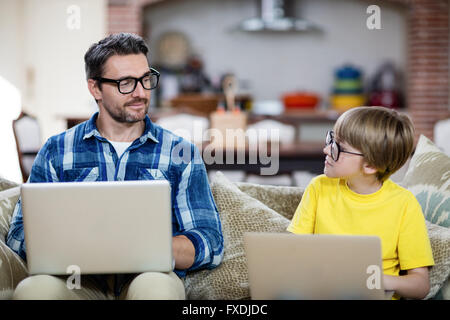 Father and son using laptop in living room Stock Photo