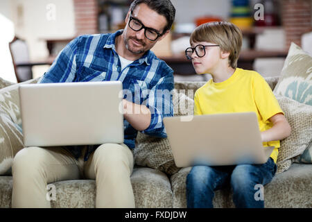 Father and son using laptop in living room Stock Photo