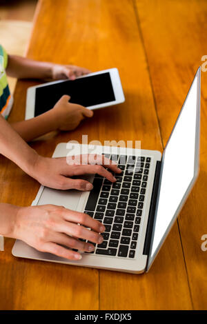 Hands using laptop and digital tablet at table Stock Photo