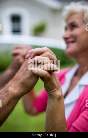 Close-up of senior couple holding hands in yard Stock Photo