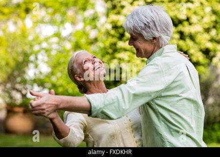 Smiling senior woman looking up while dancing with man Stock Photo