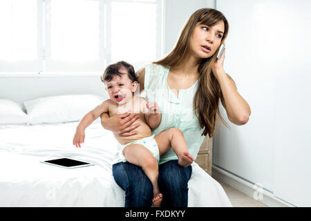 Son crying while mother talking on mobile phone Stock Photo