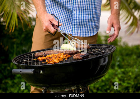 Mid section of man preparing food on barbecue grill Stock Photo