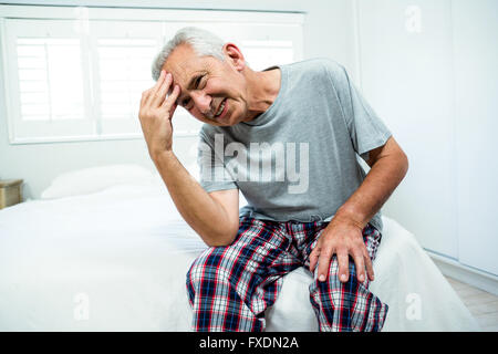 Frustrated senior man on bed at home Stock Photo