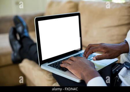 Man sitting on sofa and using laptop Stock Photo