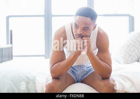 Tensed young man sitting on bed Stock Photo