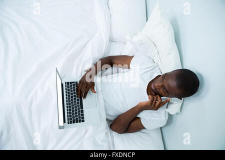 Man looking at laptop while talking on phone Stock Photo