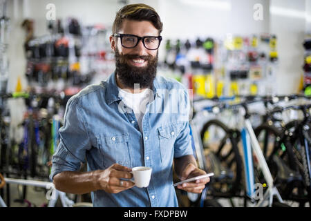 Bike mechanic checking at smartphone and having coffee Stock Photo