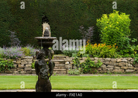 A beautiful, private, traditional, landscaped, country garden, West Yorkshire, England  - ornamental cherub fountain, lawn and raised flower border. Stock Photo