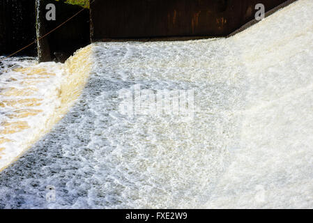 Shallow and sparkling freshwater stream down an overflow in Lyckeby, Sweden. The water is foaming and bubbling in the sunshine. Stock Photo