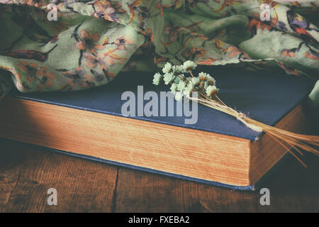 romantic scene of old book on wooden table. vintage filtered and toned image Stock Photo