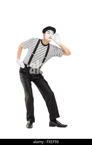 Vertical shot of a male mime artist trying to hear something isolated on white background Stock Photo