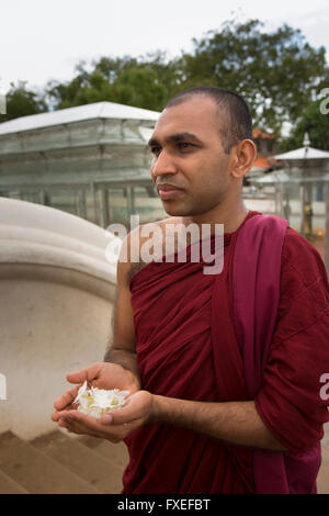 Sri Lanka, Kataragama, Kiri Devale, Buddhist monk with handful of jasmine as offering Stock Photo