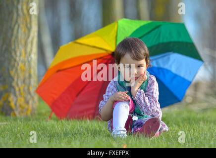 A little girl with a rainbow umbrella in forest Stock Photo