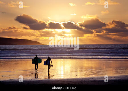 Two body boarders at sunset on Gwithian beach Cornwall, UK Stock Photo