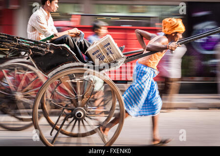 Panning photography image of a man pulling a hand drawn rickshaw on the streets of Kolkata in India Stock Photo