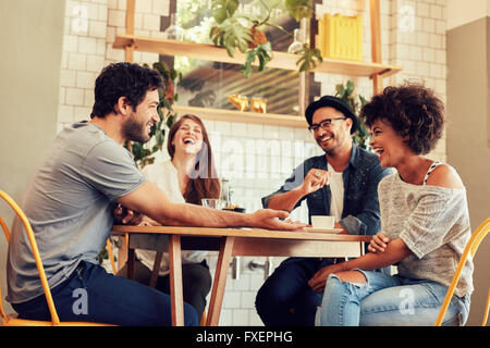 Young friends having a great time in restaurant. Group of young people sitting in a coffee shop and smiling. Stock Photo