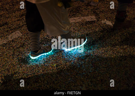 View on neon glowing shoes worn by a Basel carnival participant. The light gives the scene an eerie look. Stock Photo