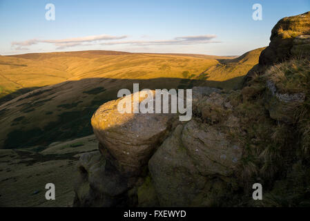 Gritstone rocks on the hills above Hayfield in Derbyshire. Late afternoon sunlight on the hills. Stock Photo