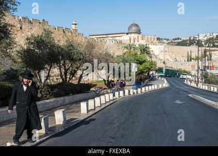 Orthodox Jew on Ma'ale HaShalom street called Pope's Road in Jerusalem, Israel. Al-Aqsa Mosque on background Stock Photo