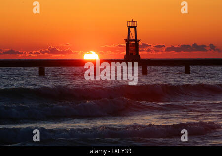 The sun rises behind the North Avenue Beach lighthouse at sunrise in Chicago, Illinois, United States of America. Stock Photo