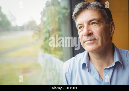 Thoughtful man looking through a window Stock Photo