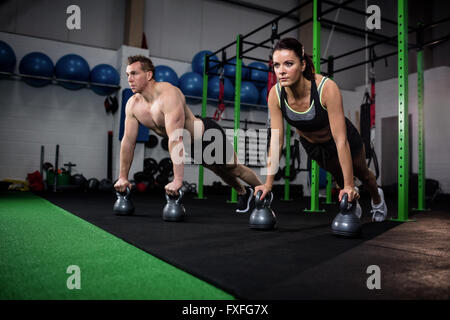 Man and woman doing push ups with kettlebell Stock Photo