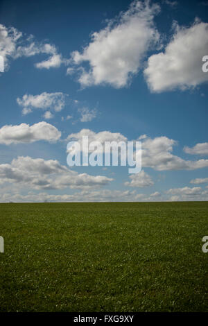Beautiful day fluffy clouds in blue sky above grassy hill Stock Photo